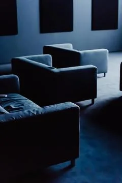 Dark Private Cinema Room with Sofas Illuminated by the Screen Stock Photos
