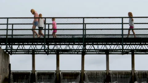 Dark Rail Bridge With Group Of Young Girls Walking Pass And One More Follows Video stock 200859375