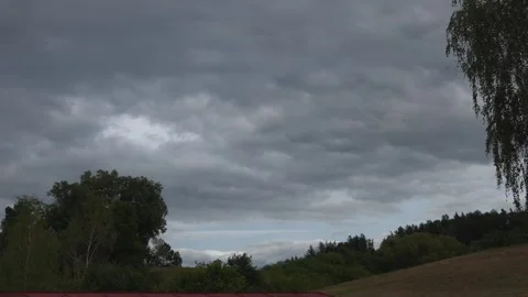 Dark rain clouds moving across the sky above a rural landscape timelaps Stock Footage 345582606
