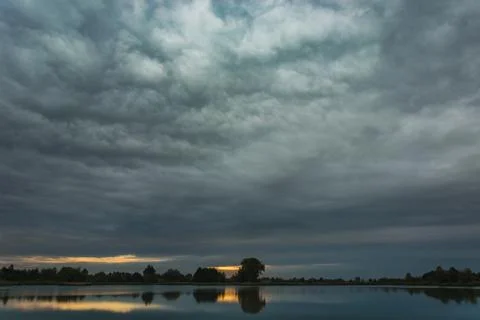 Dark rainy clouds rolling over the lake Stock Photos