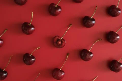 Dark red cherries on bright red background Stock Photos