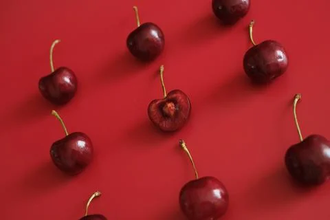 Dark red cherries on red background flat lay Stock Photos