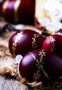 Dark red Easter eggs with a gold pattern, vintage wooden background, selectiv Stock Photos