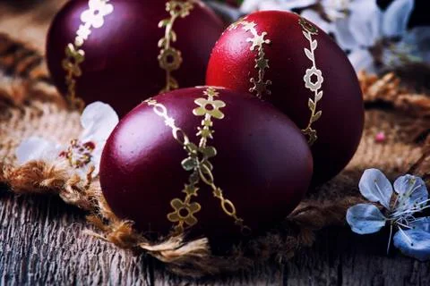 Dark red Easter eggs with a gold pattern, vintage wooden background, selectiv Stock Photos