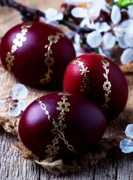 Dark red Easter eggs with a gold pattern, vintage wooden background, selectiv Stock Photos