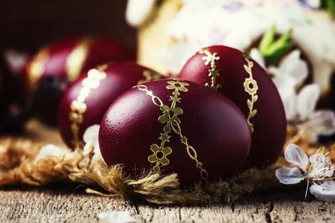 Dark red Easter eggs with a gold pattern, vintage wooden background, selectiv Stock Photos