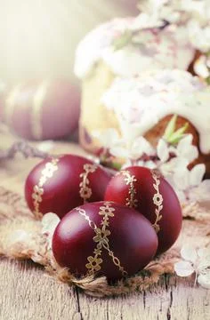 Dark red Easter eggs with gold pattern, apricot flowers,  rustic wooden backg Stock Photos