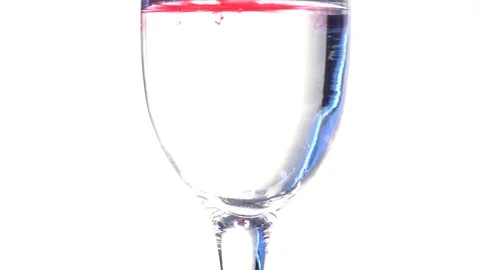 Dark red ink dropping in glass of water Stock Footage