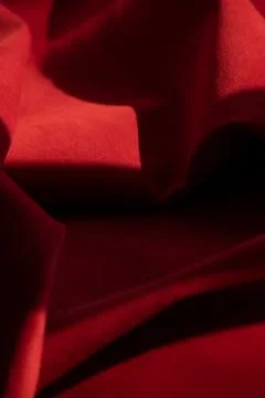 Dark red matte background of suede fabric, closeup. Velvet texture of seamles Stockfoto's