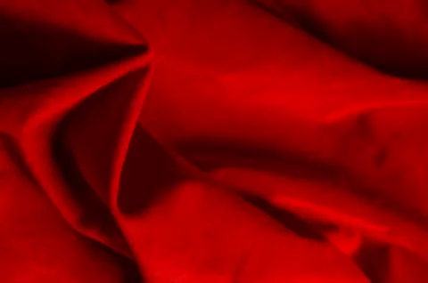 Dark red matte background of suede fabric, closeup. Velvet texture of seamles Stockfoto's