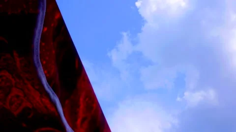 Dark red parasol flutters in the wind against blue sky with a big fluffy cloud Video stock 134909138