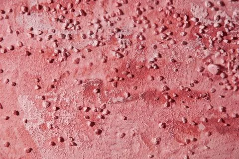 Dark red plaster background wallpaper with a smears and small pebbles Stock Photos