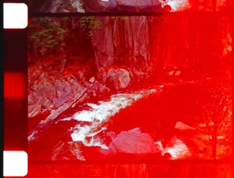 Dark river, pine trees, rocky cliffs w/ analog film artifacts light leak (16mm) 動画素材 252382623