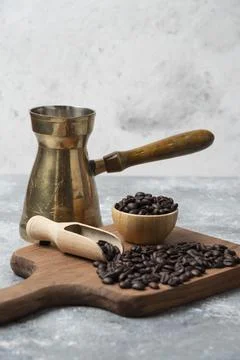 Dark roasted coffee beans and coffee maker on wooden cutting board Stock Photos