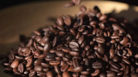 Dark roasted coffee beans falling, showcasing vibrant texture and aroma of Vídeos de archivo 276547469