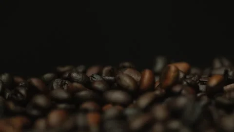 Dark roasted coffee beans falling on a black background. Slow motion Stock Footage 300242905