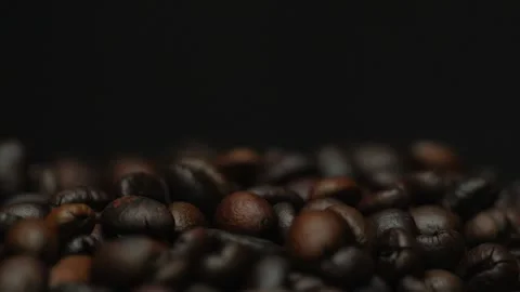 Dark roasted coffee beans falling on a black background. Slow motion Stock Footage 300242912