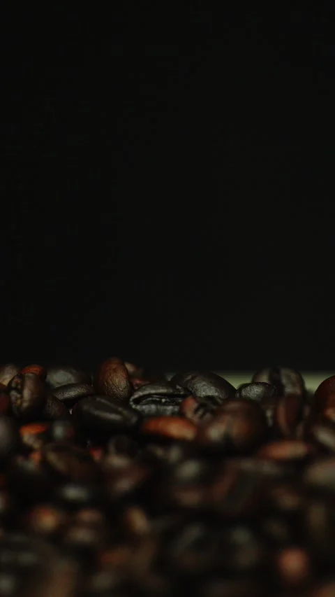 Dark roasted coffee beans falling on a black background. Vertical video Stock Footage 300243197