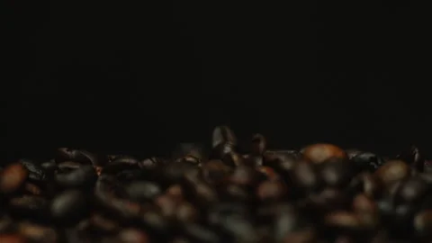 Dark roasted coffee beans falling on a black background. Slow motion Stock Footage 300243319