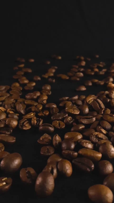 Dark roasted coffee beans gliding on a black background Stock Footage 340552593