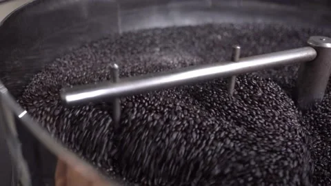 Dark roasted coffee grains being mixed inside of a roaster machine cooling tray Stock Footage 219592393