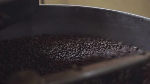 Dark roasted coffee grains being mixed inside of a roaster machine cooling tray Stock Footage 219592718