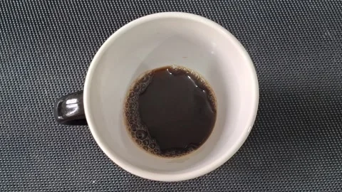Dark roasted coffee swirling inside white ceramic mug motion video footage Video stock 339249038