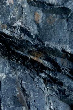Dark rocky cliff surface featuring a prominent diagonal shadow fracture Stock Photos