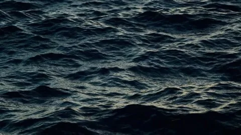 Dark, rolling ocean waves at night, a deep blue monochrome seascape. Stock Footage 297534692