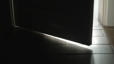 In a dark room, a door opens and bright light bursts in. Stock Footage 236299190