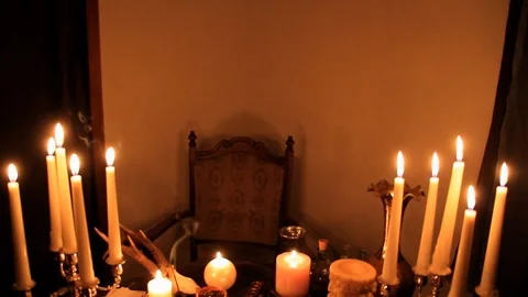 In a dark room on a round esoteric table candles are burning, animal skulls a Stock Footage 125651553