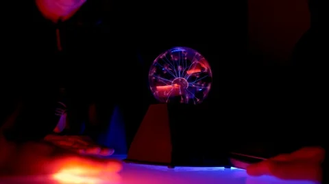 In a dark room on table, there is a Tesla ball. People put their palms on table. Stock Footage 111724527