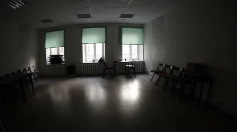Dark room with three windows full on light and chairs standing along walls Stock Footage 51555731