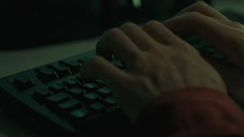 In a dark room, an unseen hacker programmer focuses on typing on a laptop co Stock Footage 254885031
