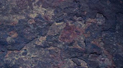 The dark rough texture of the stone with peeling rusty fragments. Background Stock-Fotos