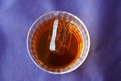 Dark rum drink with ice on a blue background Stock Photos