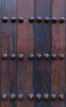 Dark rustic wooden door panel with decorative studs Stock Photos