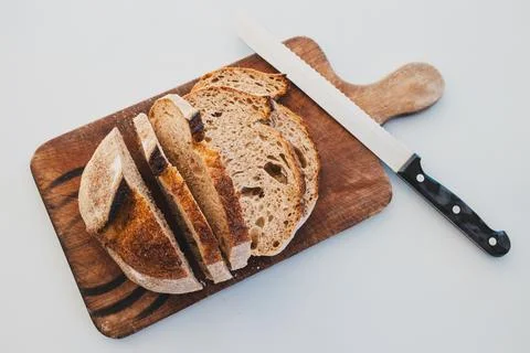 Dark rye bread cut into slices on rustic chopping board, simple healthy food Stock Photos