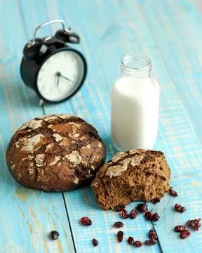 Dark rye bread loaf with crispy crust, glass of milk and alarm clock. Freshly Stock Photos