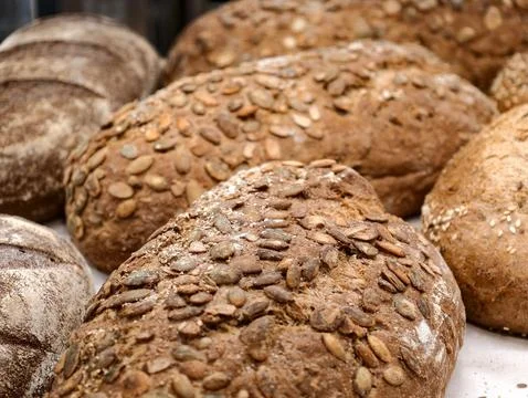 Dark rye bread with pumpkin seeds covering the crust displayed in a bakery,.. Stock Photos