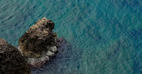 Dark sea stack in clear turquoise coastal water, aerial footage 库存影片 348709947