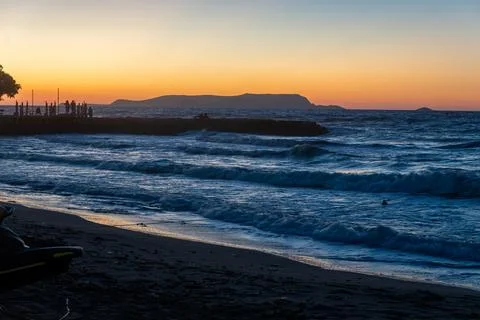 Dark sea waves rolling on sandy beach at sunset Fotos Stock