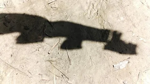 Dark shadow of a person walking on a textured concrete ground surface 스톡 사진