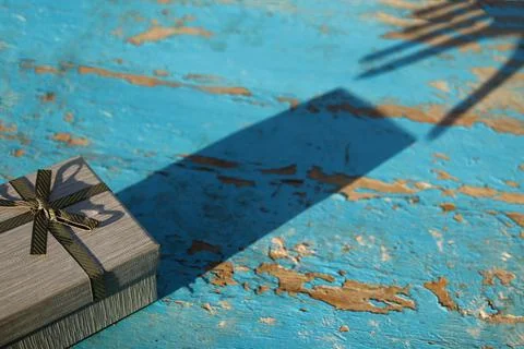 Dark shadow reflection grey gift box with shadow reflection hand on blue, tur Stock Photos