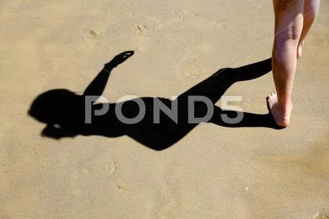 Dark shadow of the young girl on the beach sand Stock Photos