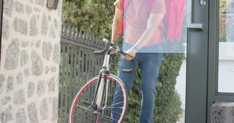 Dark shape clearing, cyclist is pushing road bicycle through glass door to exit Stock Footage 340454321