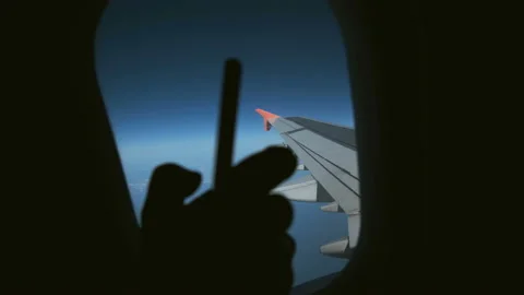 Dark silhouette of the female hand using smartphone in the airplane at window 動画素材 94030348