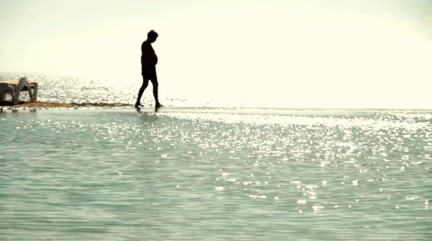 A dark silhouette image of man walking along a beach Stock Footage 1068742