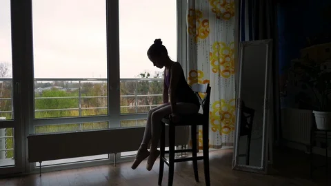 Dark silhouette of Little ballet dancer, girl in a ballet leotard, resting Stock Footage 128664047