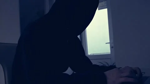 Dark silhouette of a man in a hood, hacker, internet bandit, writing on a Stock Footage 312871052